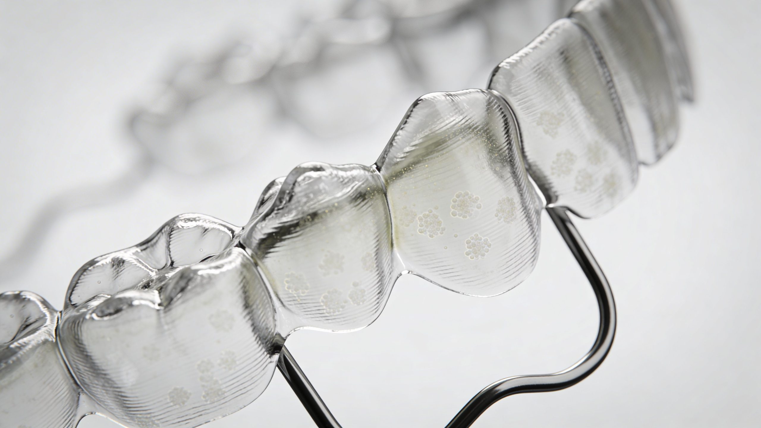 Close-up of a clear plastic Invisalign aligner tray showing visible bacterial buildup and plaque on the surface.